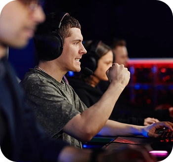 Zespół e-sportowy grający mecze na komputerach do gier, gdzie jeden gracz świętuje ważny moment, nosząc zestaw słuchawkowy podczas intensywnego meczu online.