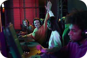 Zespół e-sportowy świętuje zwycięstwo podczas wydarzenia LAN, podnosząc ręce w górę, nosząc zestawy słuchawkowe w neonowo oświetlonej arenie gier.
