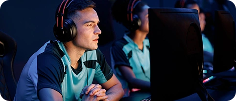 Gracze e-sportowi biorący udział w turnieju LAN, z zestawami słuchawkowymi na uszach, skupieni na potężnych komputerach do gier.